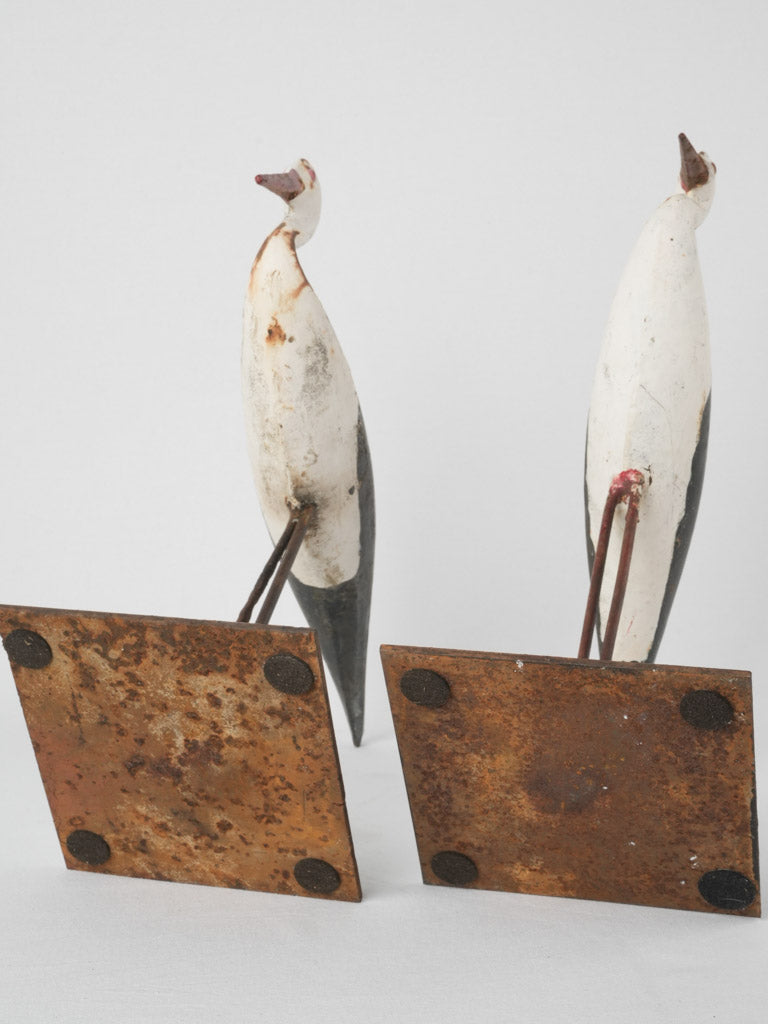 Aged, hand-painted metal stork statues