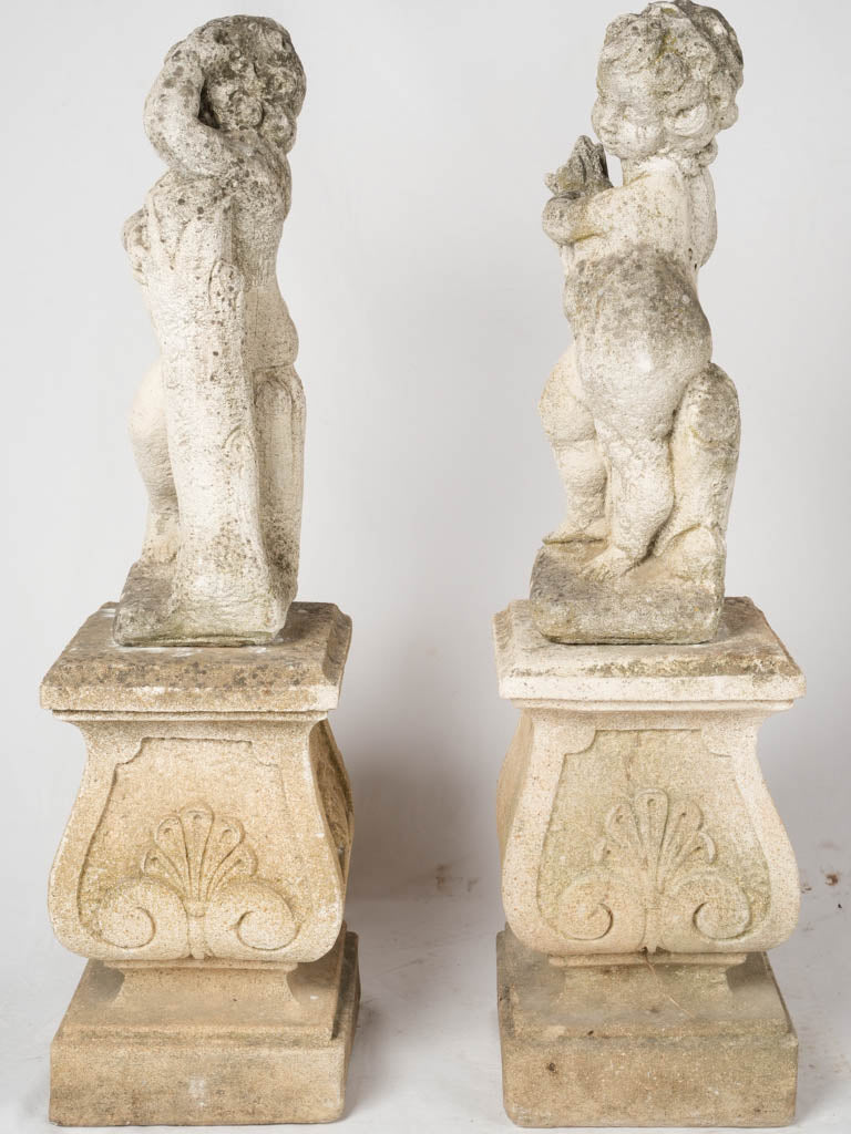 Aged reconstituted stone cherub sculptures