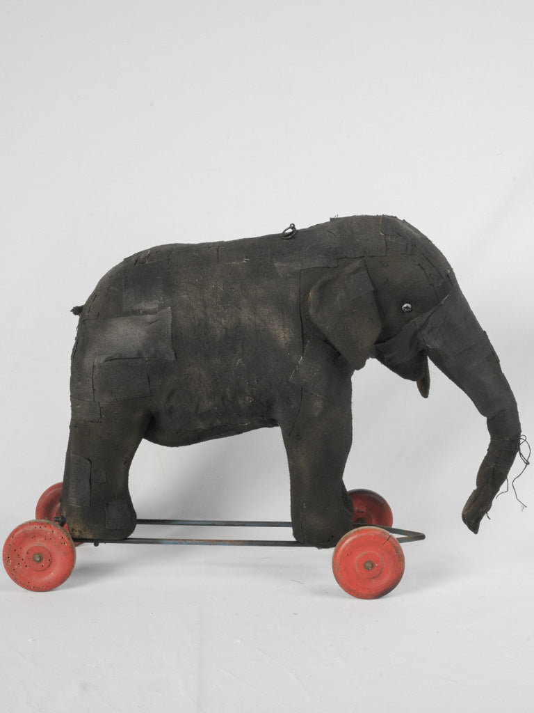 Handcrafted aged elephant on red wheels