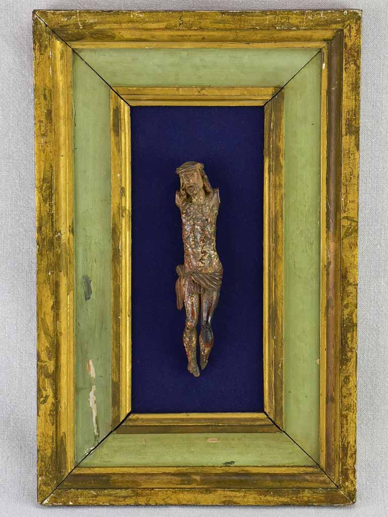 18th Century sculpted wooden Christ on blue fabric with a green and gold frame 11¾" x 18½"