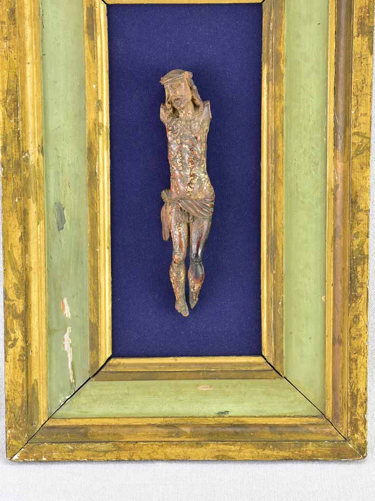 18th Century sculpted wooden Christ on blue fabric with a green and gold frame 11¾" x 18½"