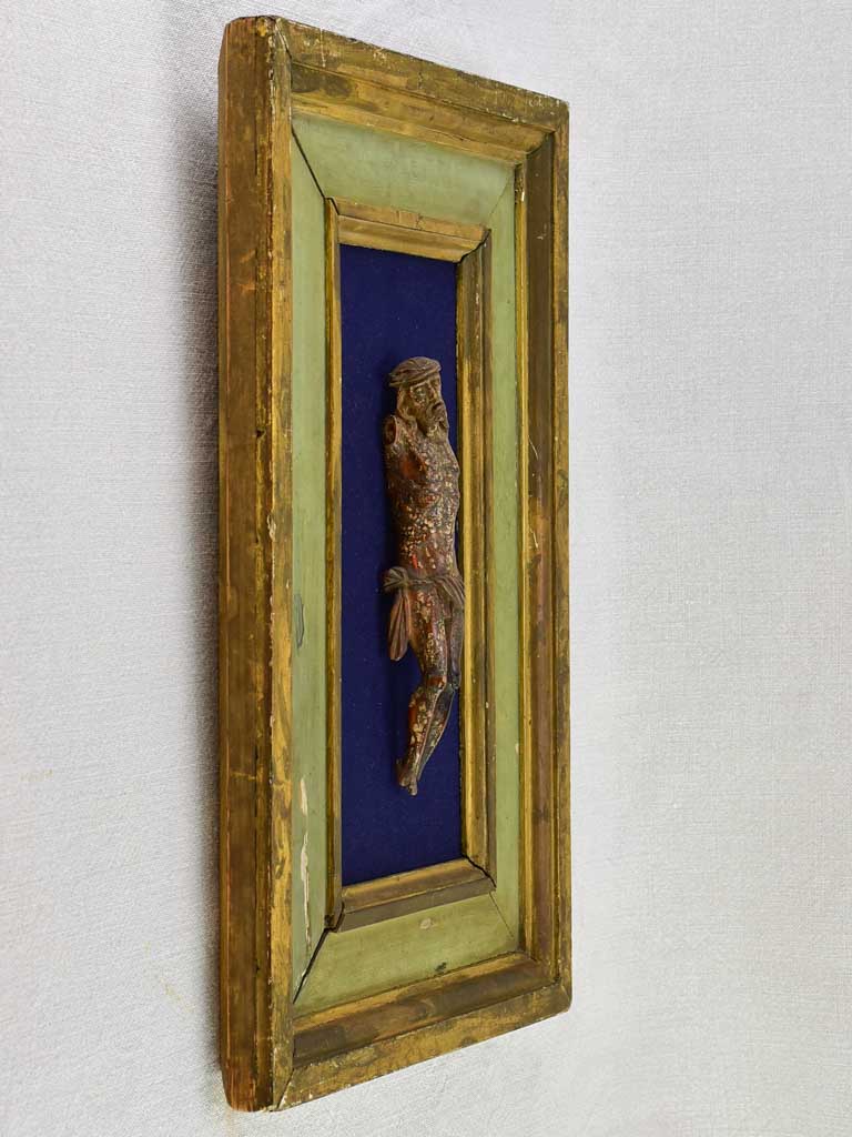 18th Century sculpted wooden Christ on blue fabric with a green and gold frame 11¾" x 18½"