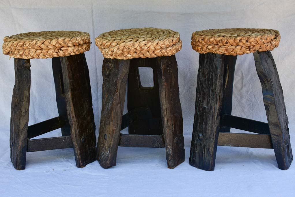 Three 1960's stools with woven seats and weighty timber and iron bases