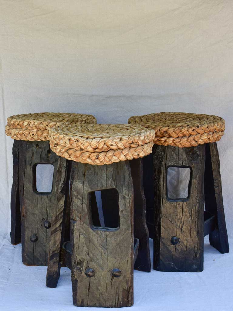 Three 1960's stools with woven seats and weighty timber and iron bases