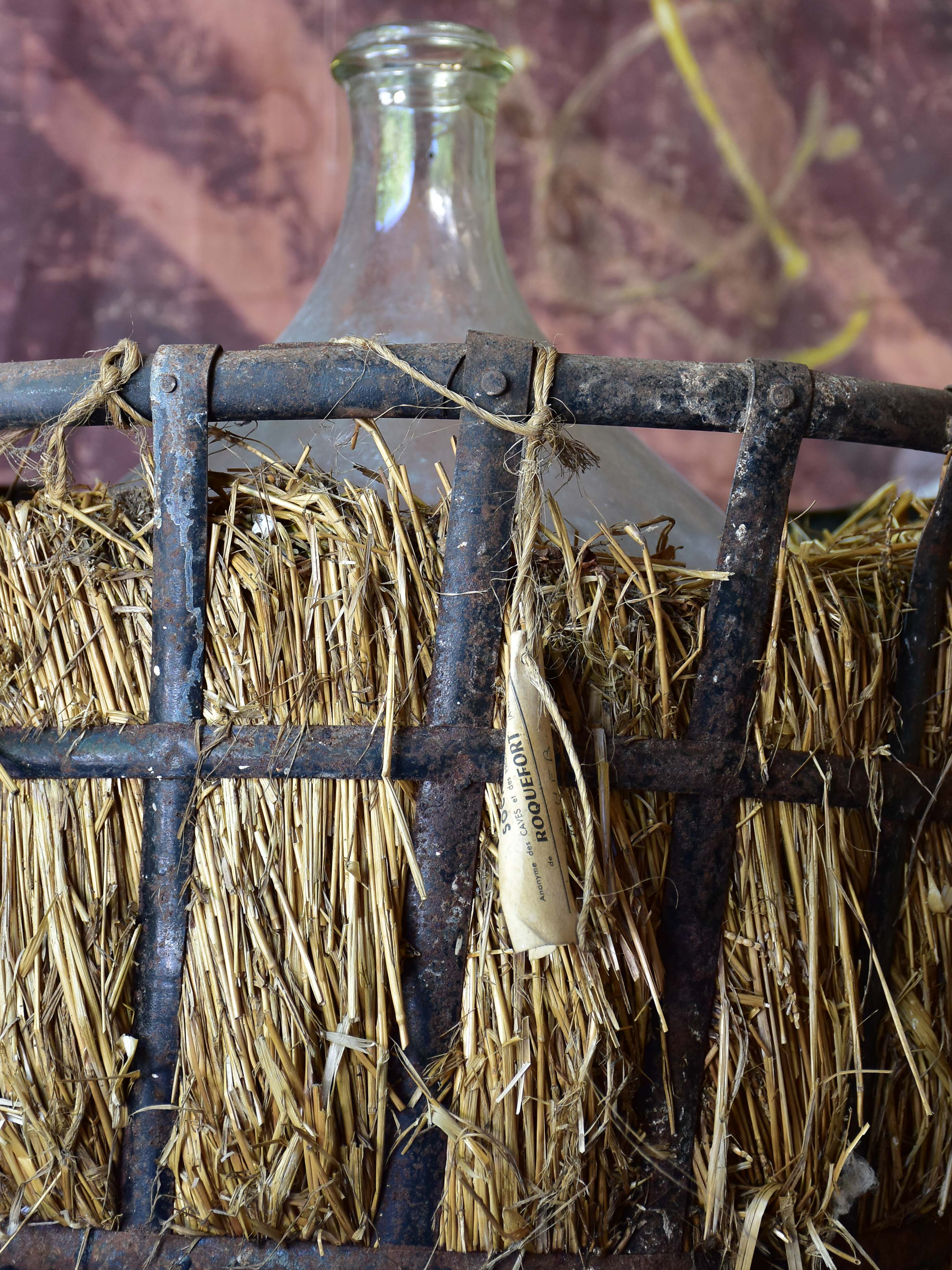 Very large antique French demijohn bottle in hay and crate