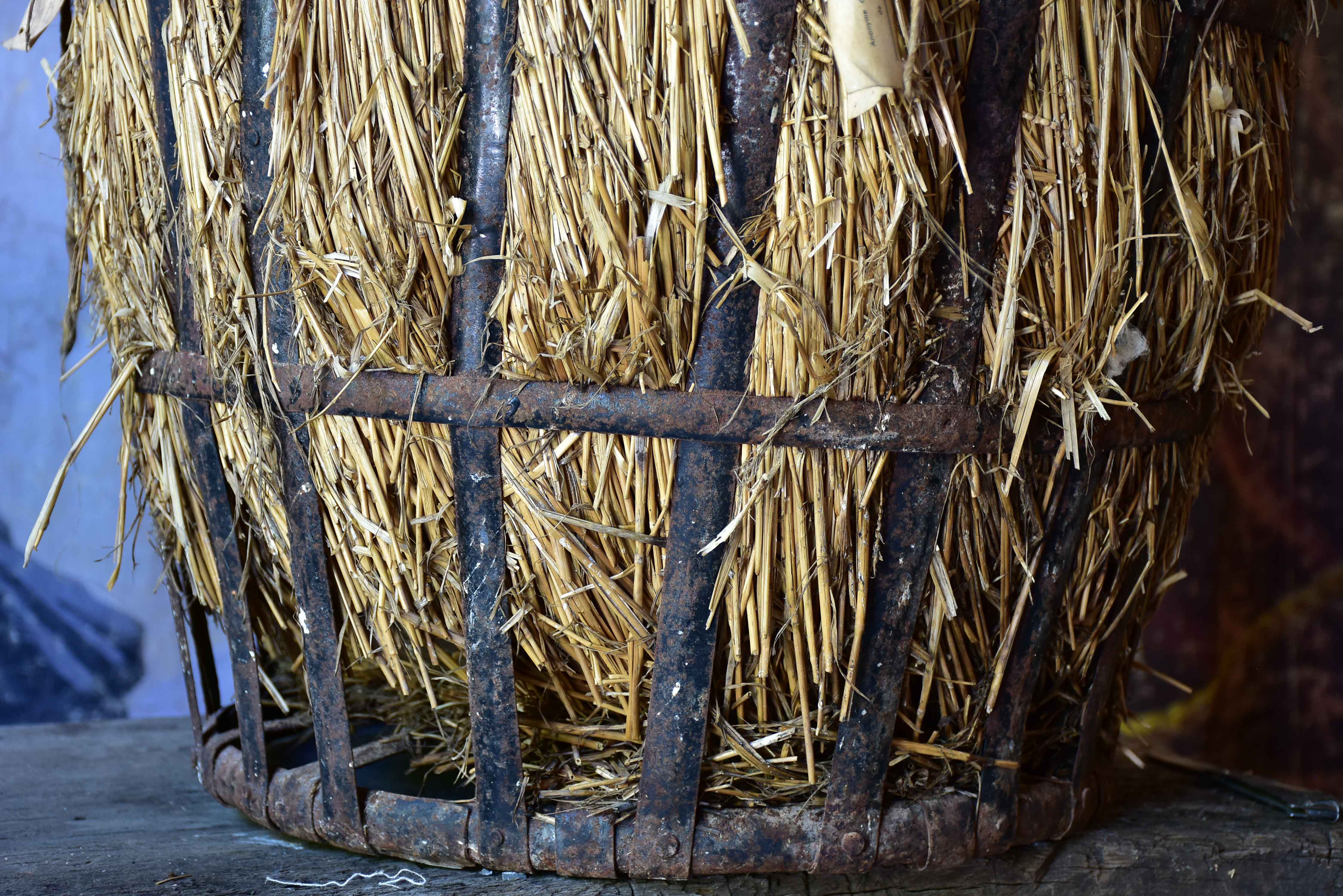 Very large antique French demijohn bottle in hay and crate