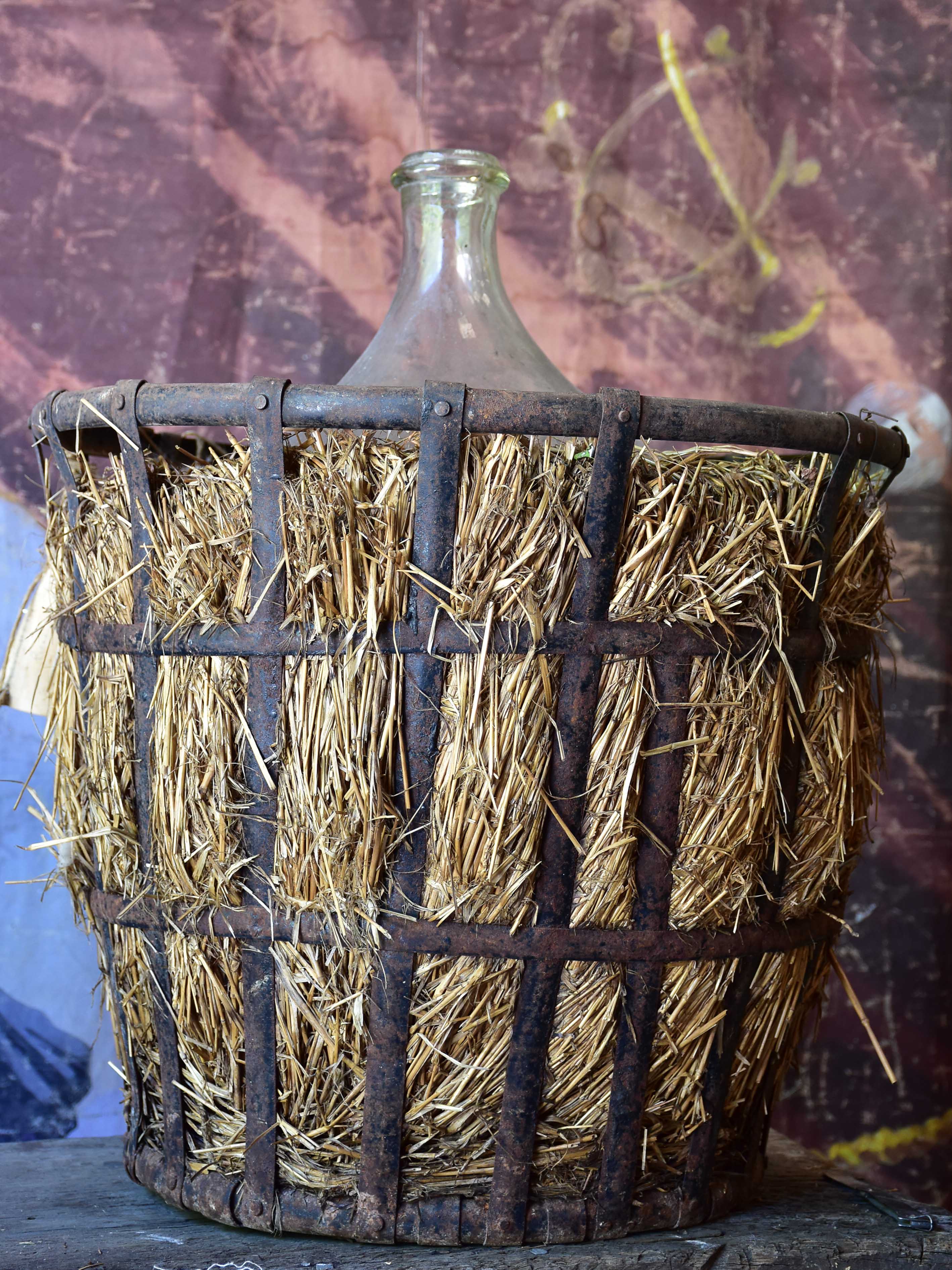 Very large antique French demijohn bottle in hay and crate