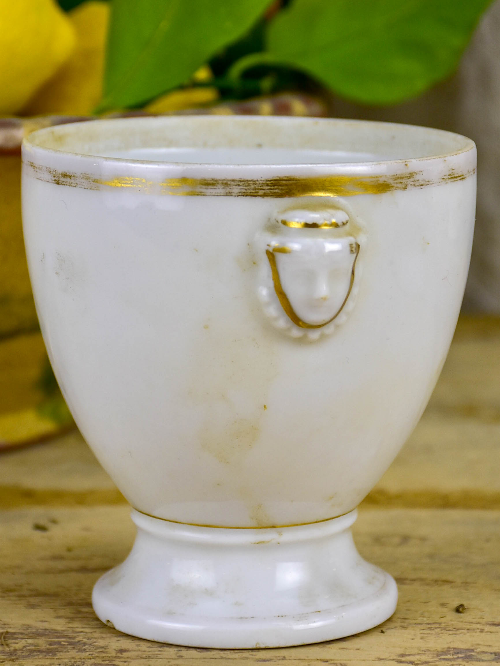 Antique French earthenware cup with face handles and gold trim