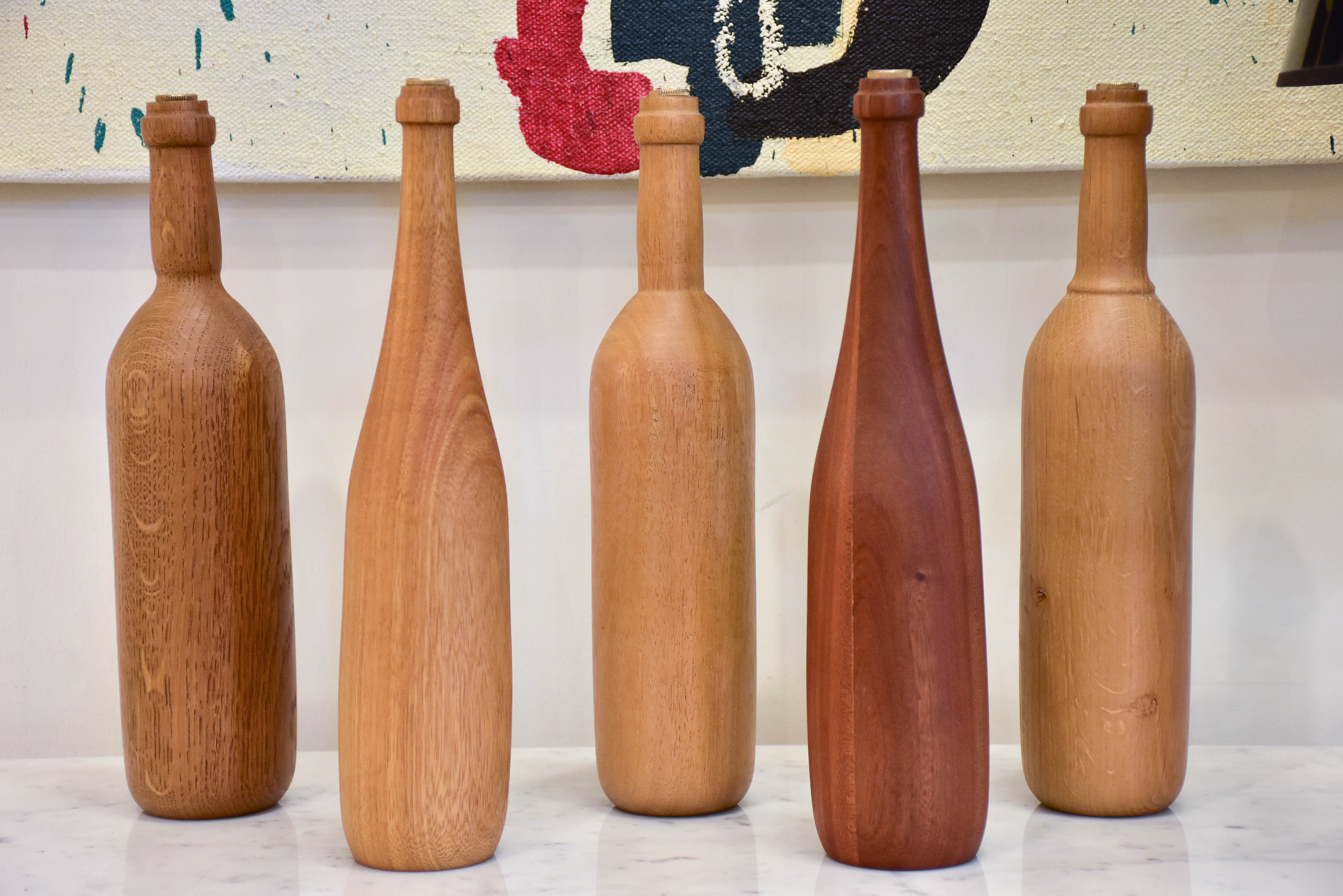 Collection of five wooden sculptures in the shape of bottles