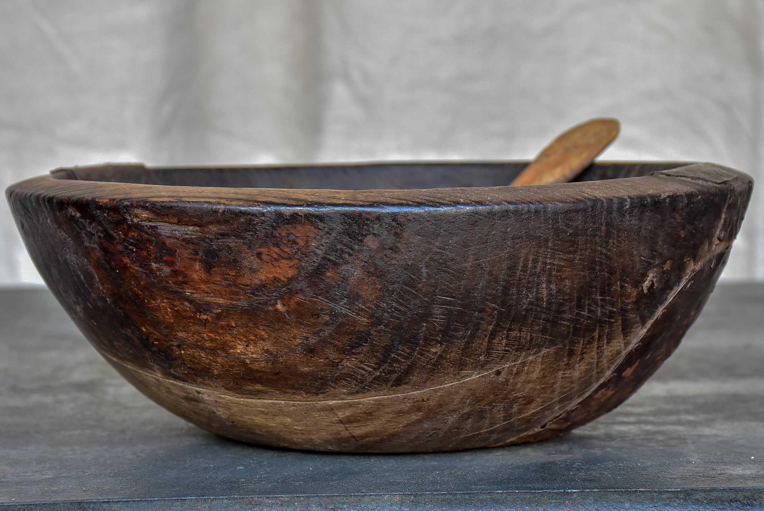 An antique French wooden bowl with repairs