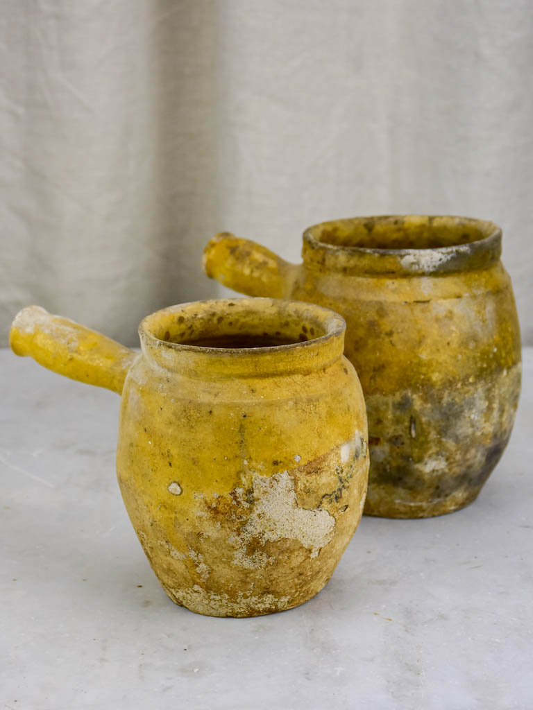 Two antique French cooking pots with one handle and yellow glaze