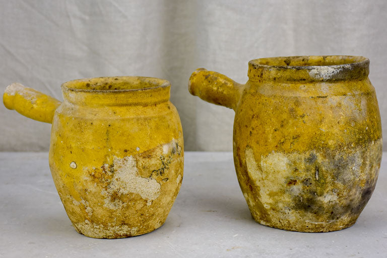 Two antique French cooking pots with one handle and yellow glaze