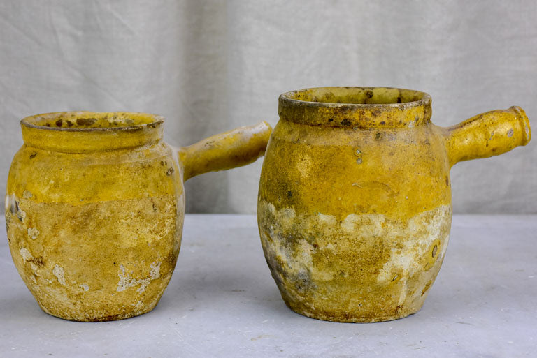 Two antique French cooking pots with one handle and yellow glaze