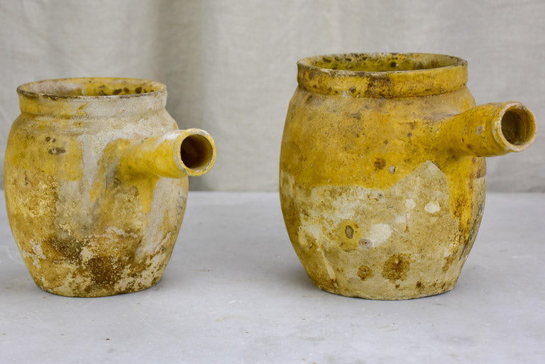 Two antique French cooking pots with one handle and yellow glaze