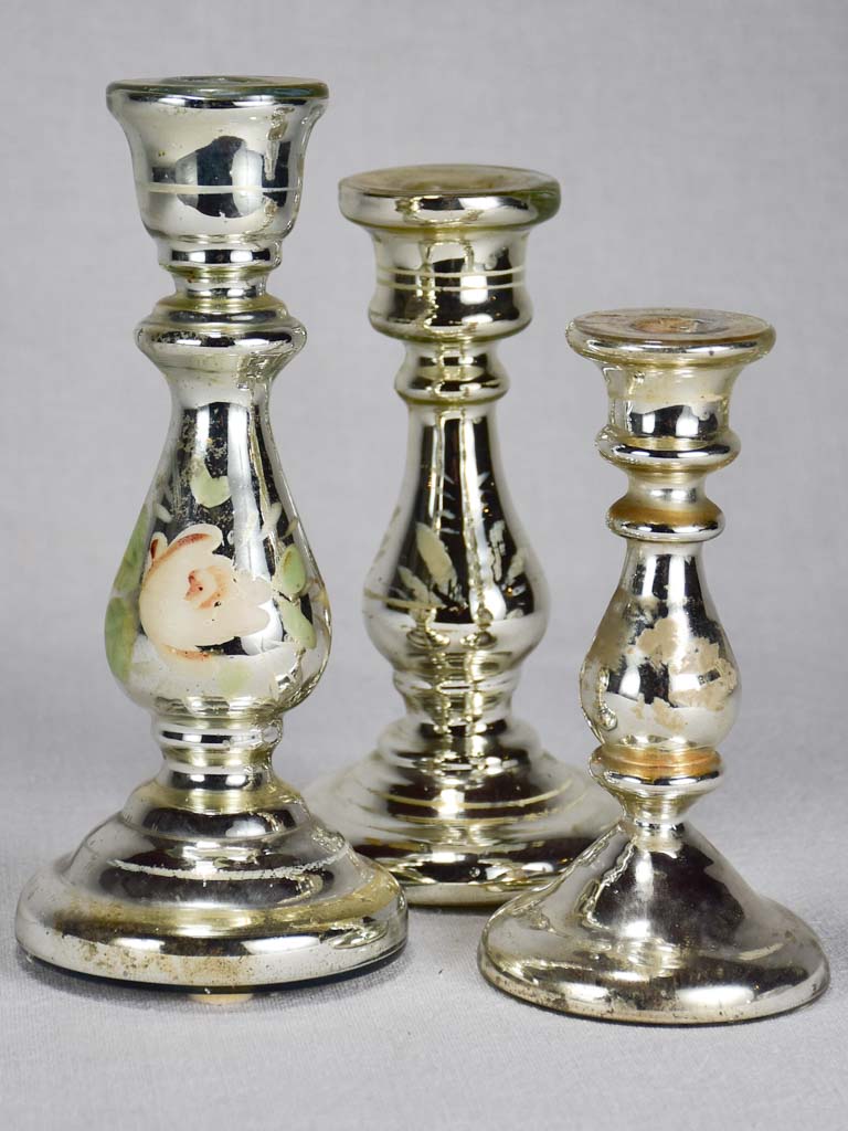 Three mercury glass candlesticks with flowers