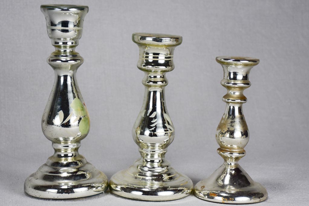 Three mercury glass candlesticks with flowers